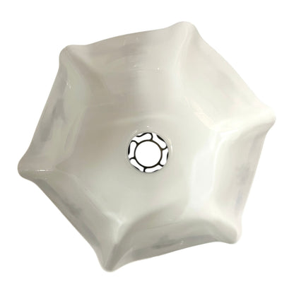 Close up of a white glass lamp shade with decorative design on a white background