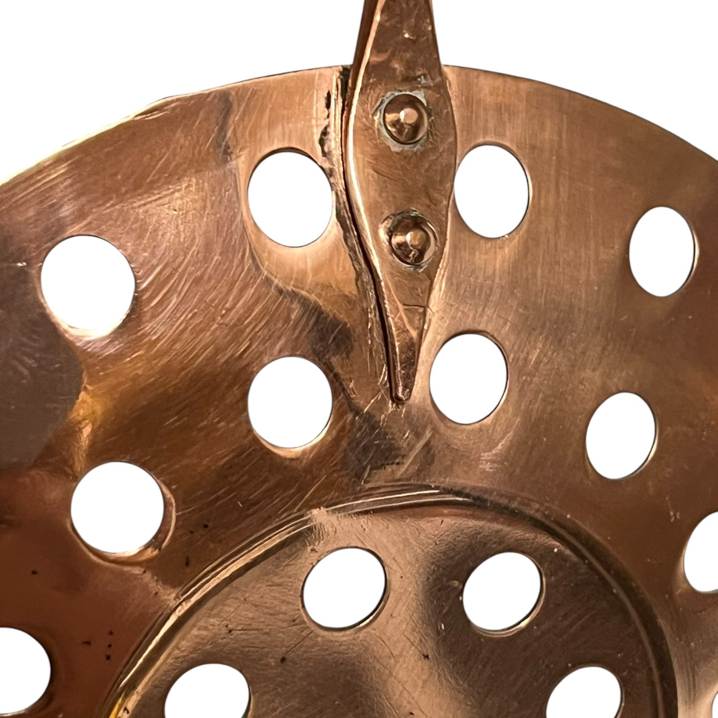 Close up of 3 copper utensils on a copper hanging bar on a white background