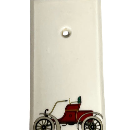 Close up of fingerplate with vintage car illustrations on a white background