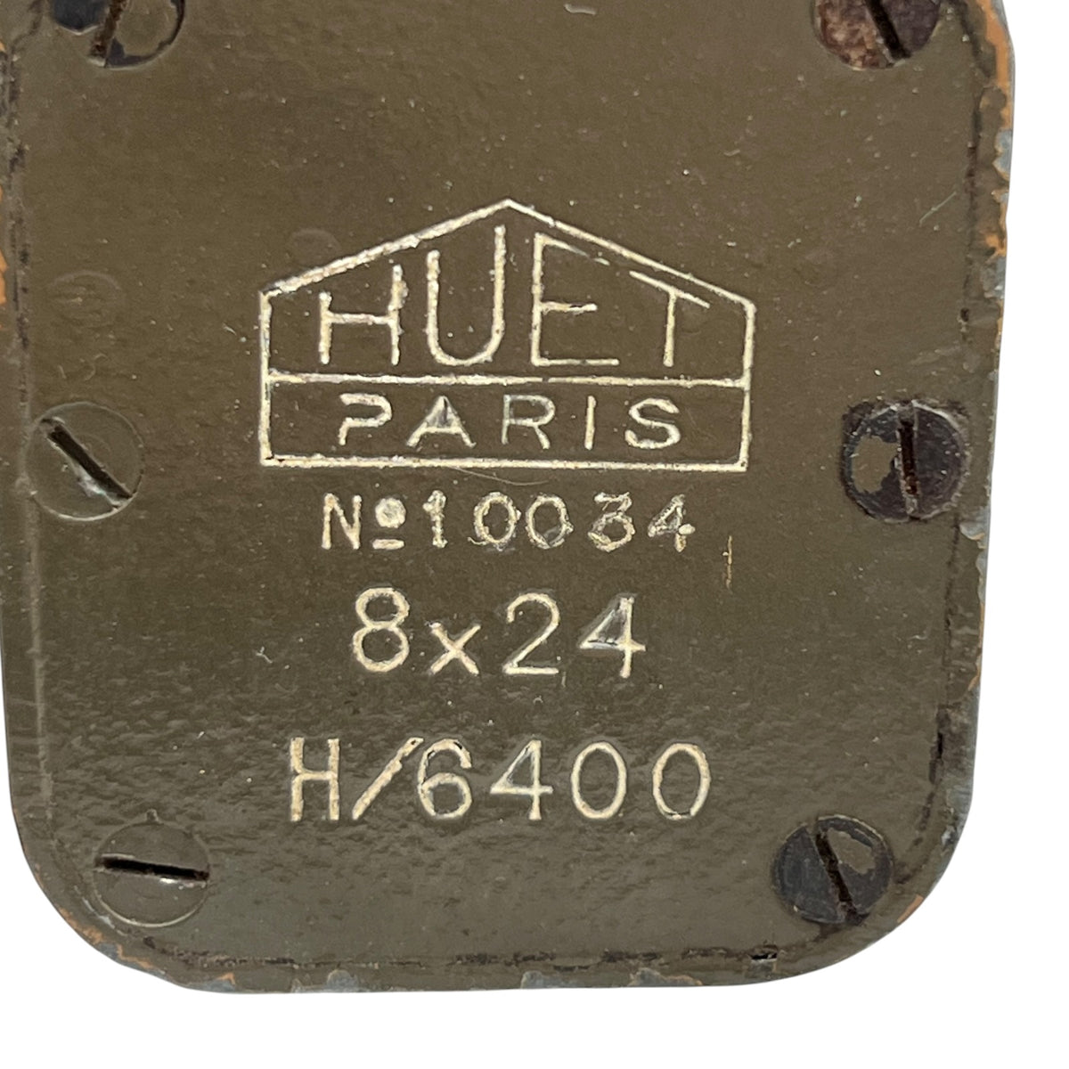 Close-up of a dark olive green metal plate with pre-drilled screw holes and embossed white text reading 'HUET PARIS', 'N°10034', '8x24', and 'H/6400'.