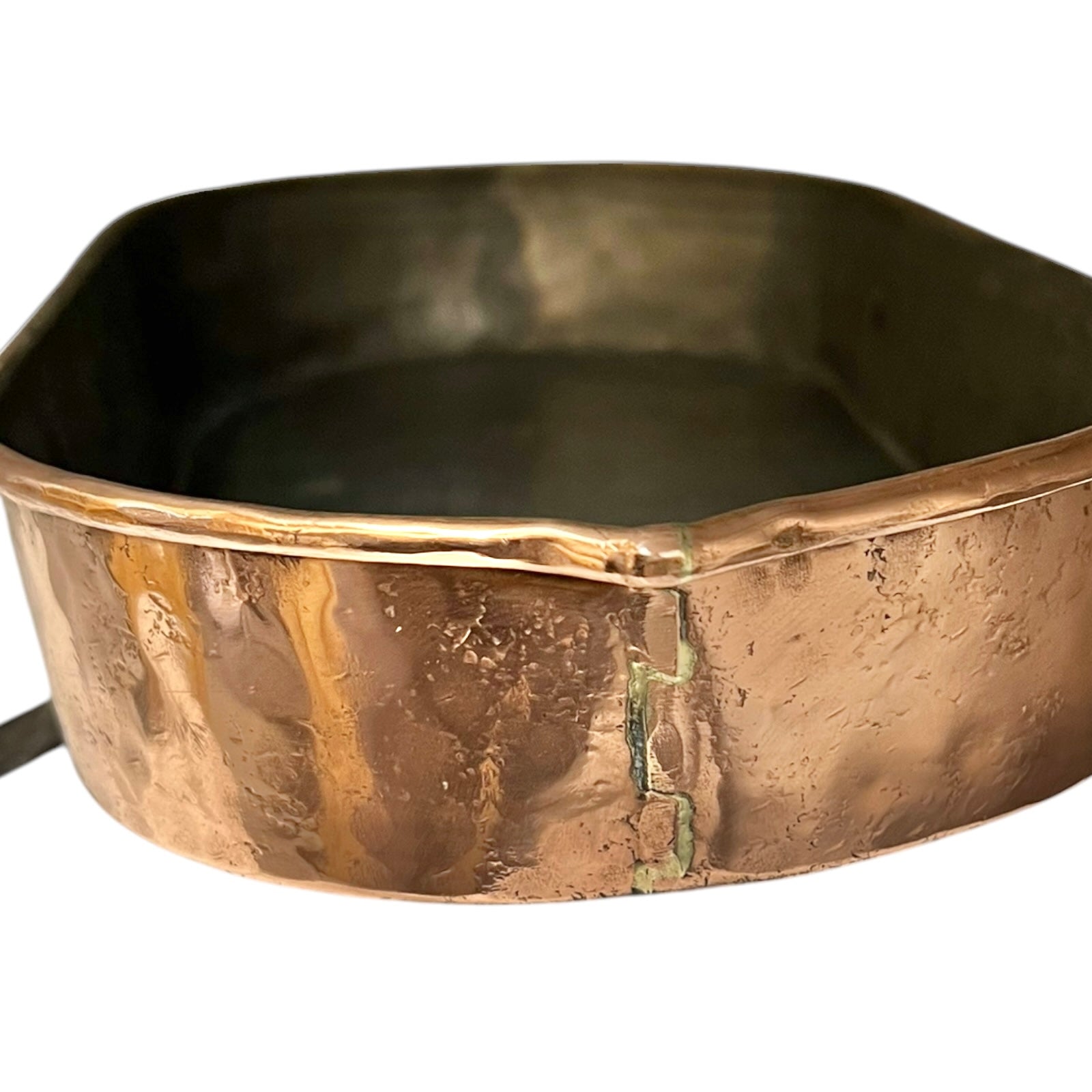 Close up of a copper roasting pan with a long handle on a white background