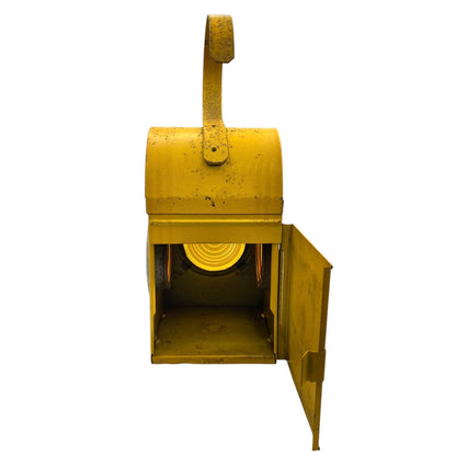 Close up of yellow vintage railway or railroad lamp with orange glass panels and a hook on a white background