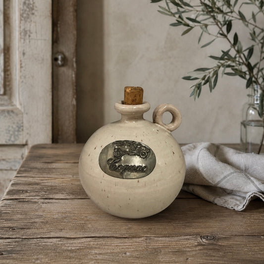 Ceramic bottle with cork stopper on a wooden surface with a neutral background