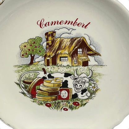 Decorative plate with a cartoon-style illustration of a barn, cow, and cheese, featuring the word 'Camembert'.