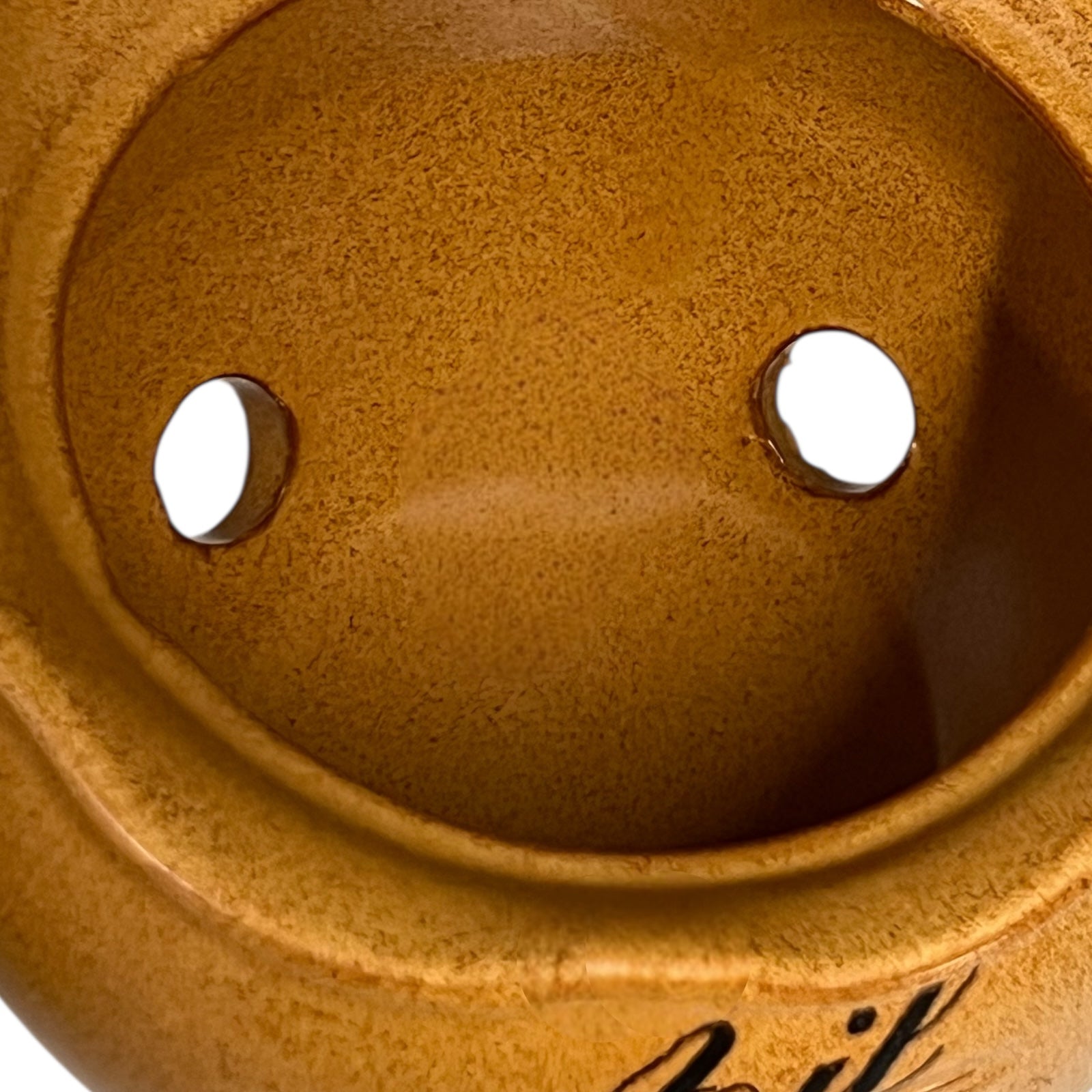 Close-up of a brown ceramic product with two holes and 'Beef' branding.