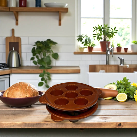 Brown snail plates with multiple holes on a wooden kitchen counter, with bread and fruits in the background.