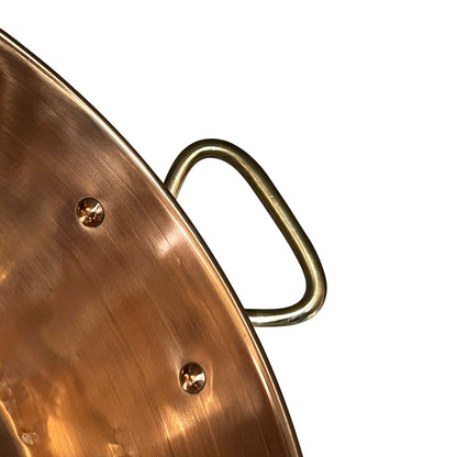Close-up of a copper up cycled sink with brass handles on a white background.