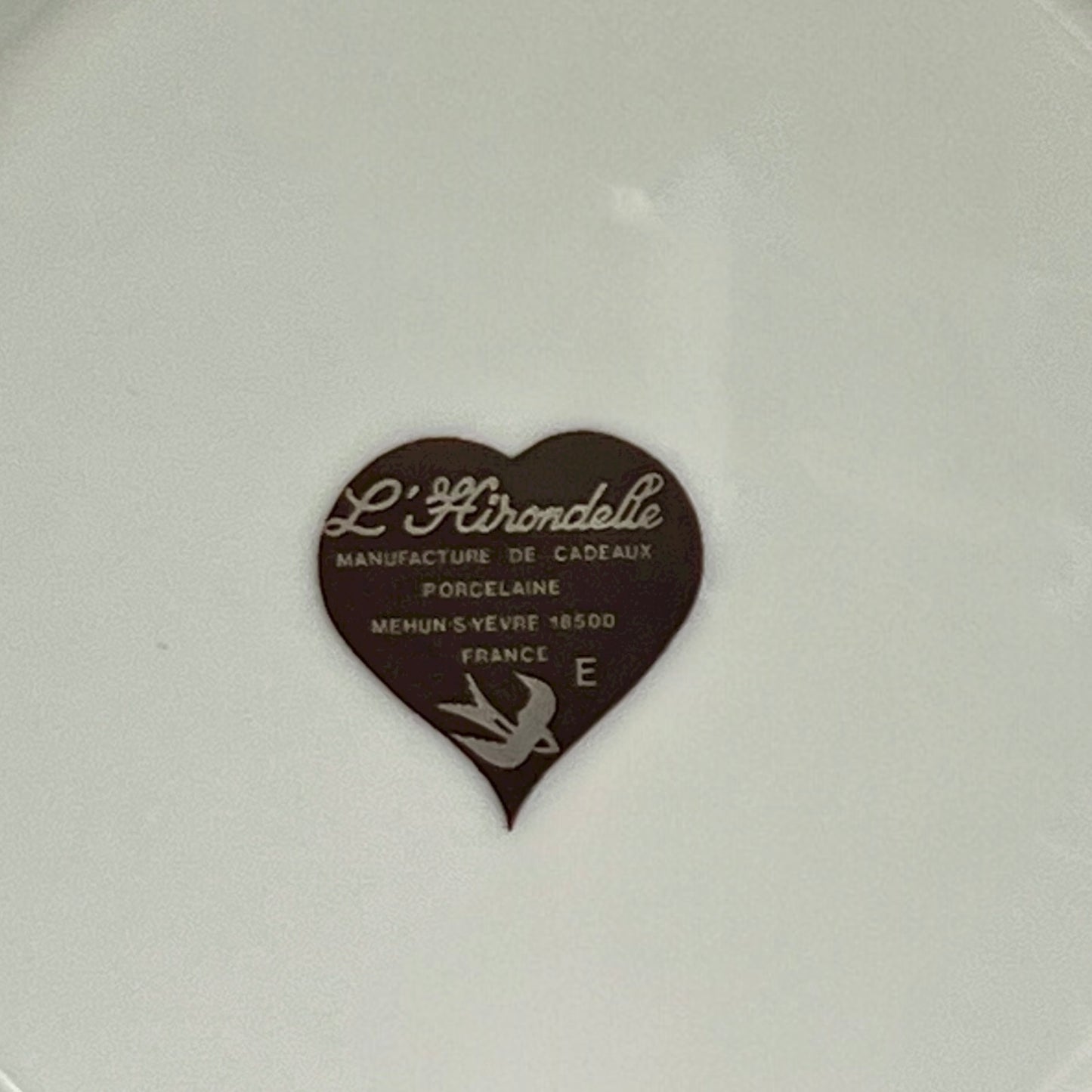 Back of a French cheese plate showing the Hirondelle makers stamp on a stand with a white background