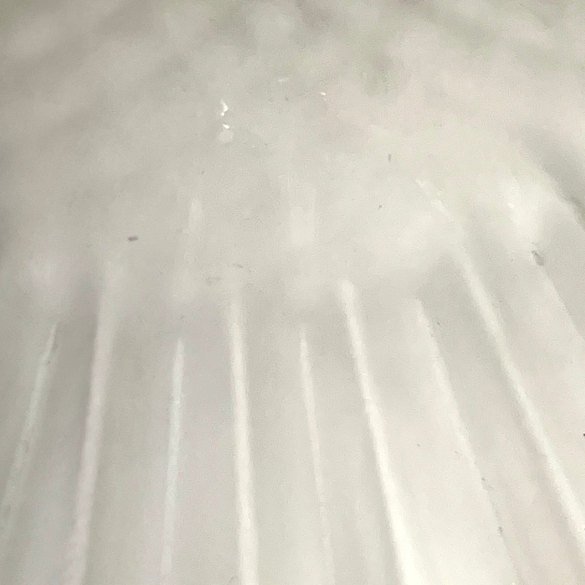 A close-up view of a frosted glass lampshade , showing vertical ridges and a slightly translucent quality.