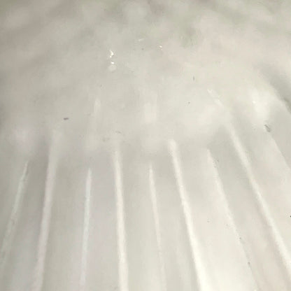 A close-up view of a frosted glass lampshade , showing vertical ridges and a slightly translucent quality.