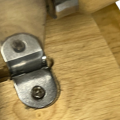 Close-up of a silver metal bracket attached to a light wood surface.