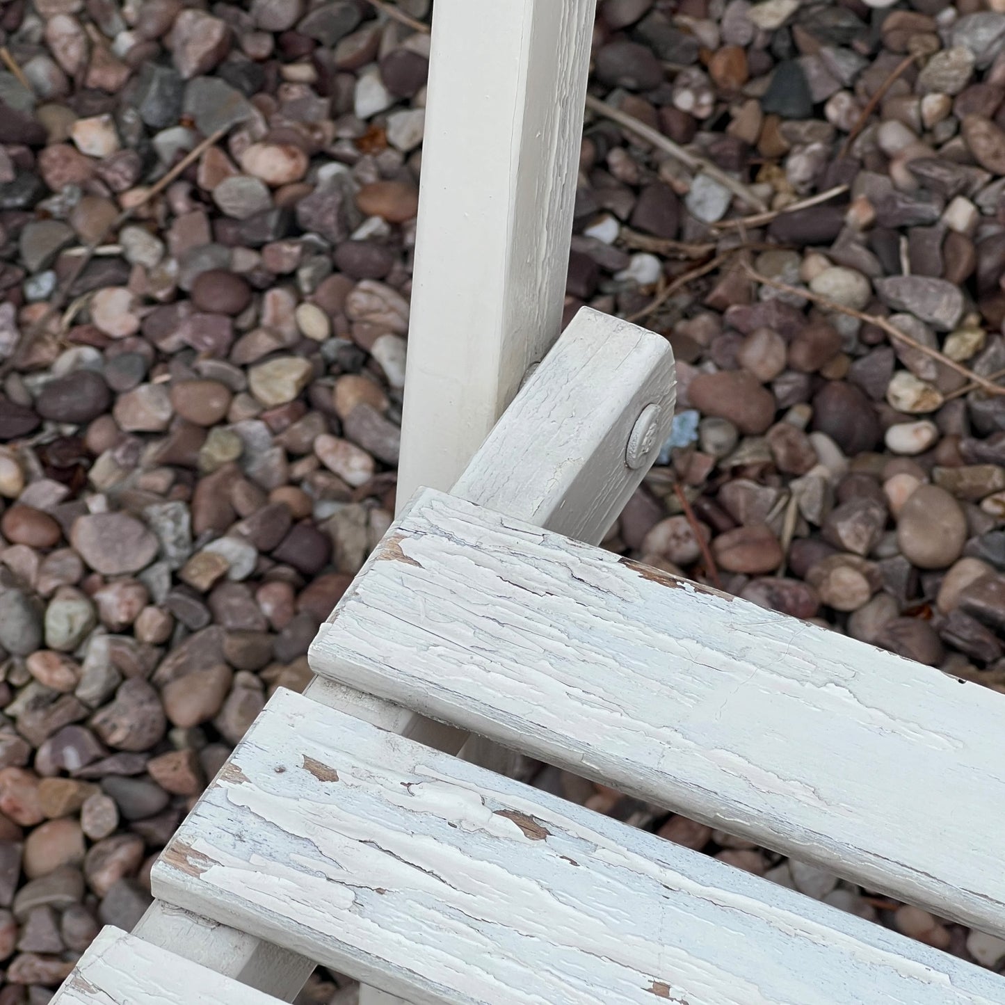 A close-up view of a painted wooden slatted garden chair set amidst a lush garden backdrop.