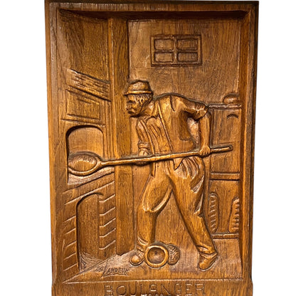 Wooden plaque with a carved scene of a man with a tool, likely a blacksmith, on a white background.
