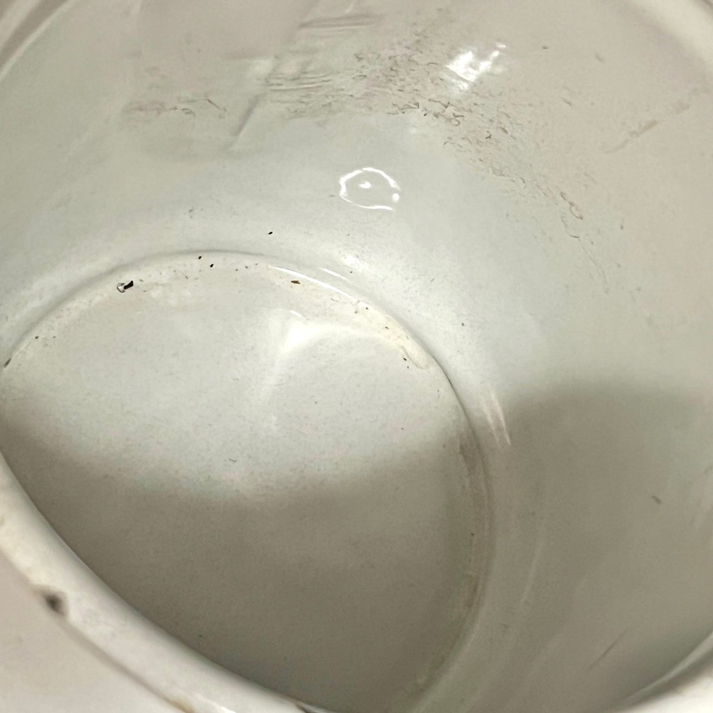 Close-up view of the inside of a white planter showing a glossy glaze with some visible dust, scratches, and minor imperfections.