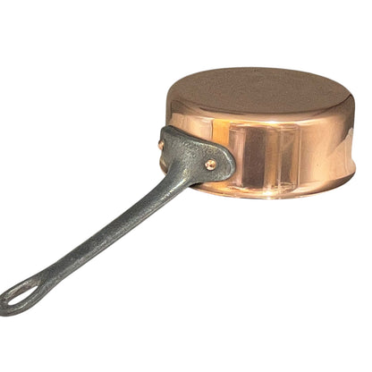 Copper saucepan with a cast iron handle on a white background