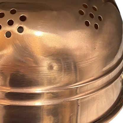 Close up of a copper colander with on a white background