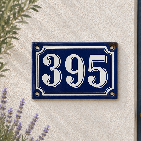 Blue and white house number sign with '395' on a light beige wall.