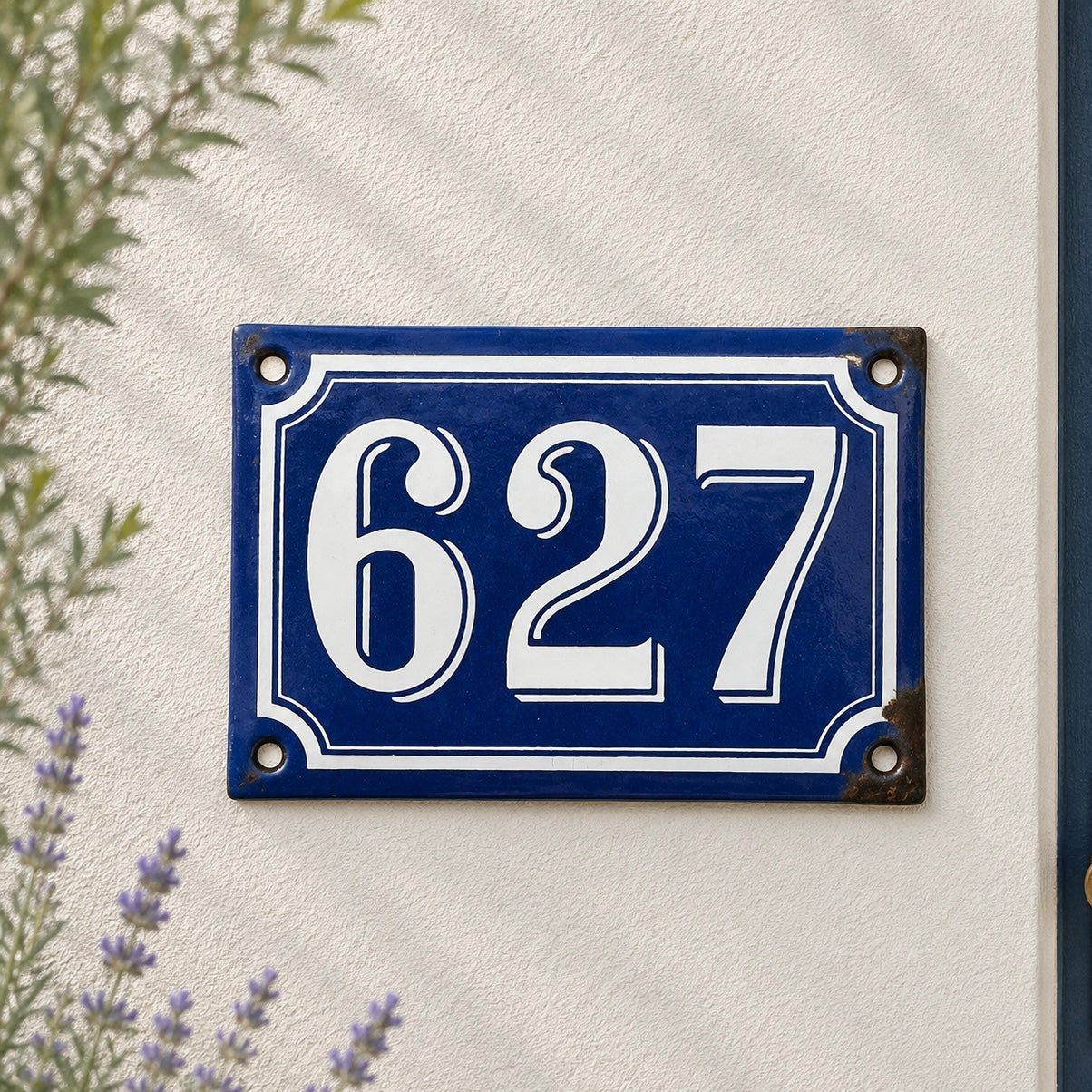 Blue and white house number plate with '627' on a white wall.
