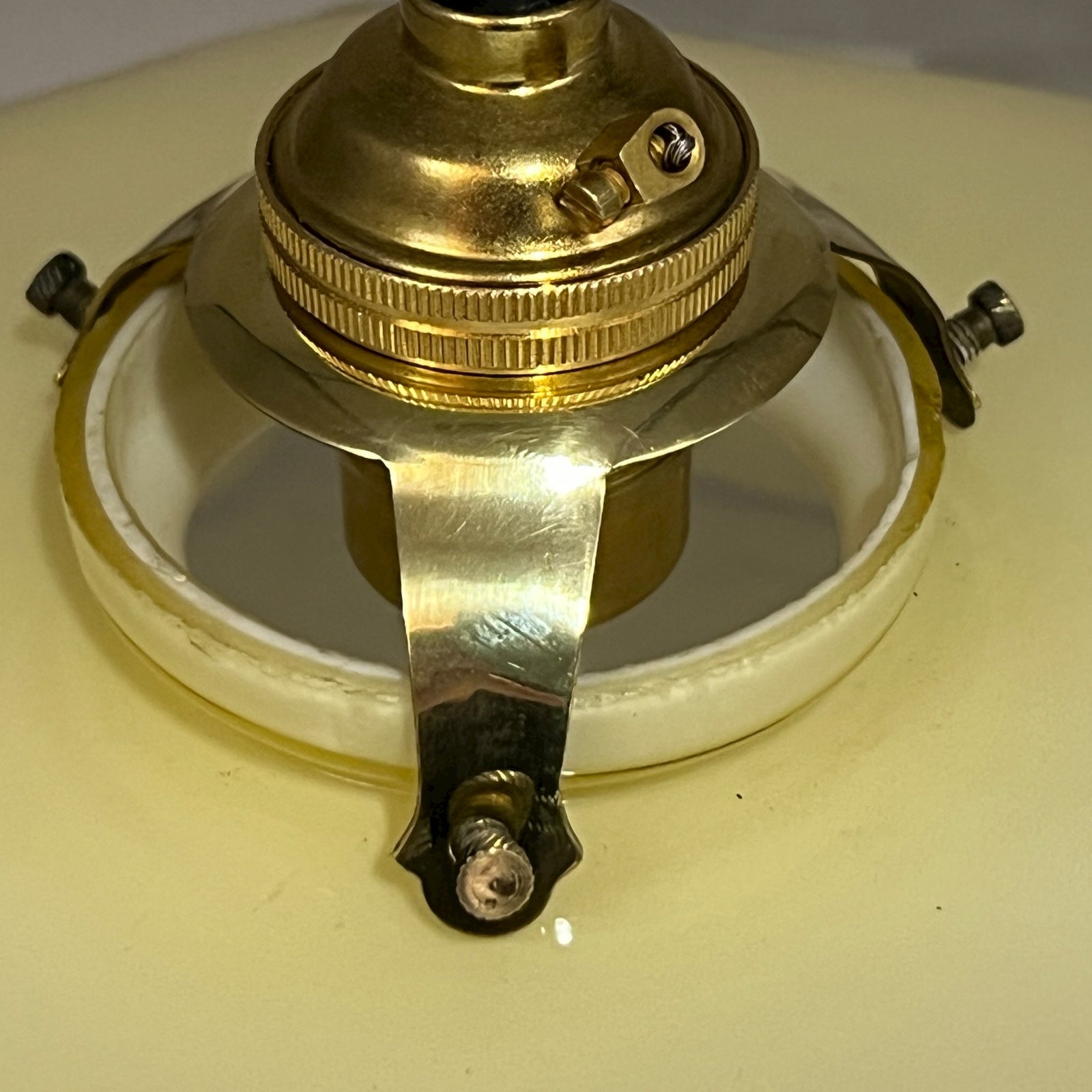 Close-up of a brass lamp fixture on a yellow glass shade