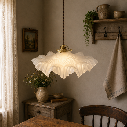 A French vintage Art Deco-style lampshade made of clear frosted glass with a frilled edge, suspended by twisted-style wiring and brass fittings, perfect for adding charm to a period room or retro home, displayed in a warm rustic home above a wooden table