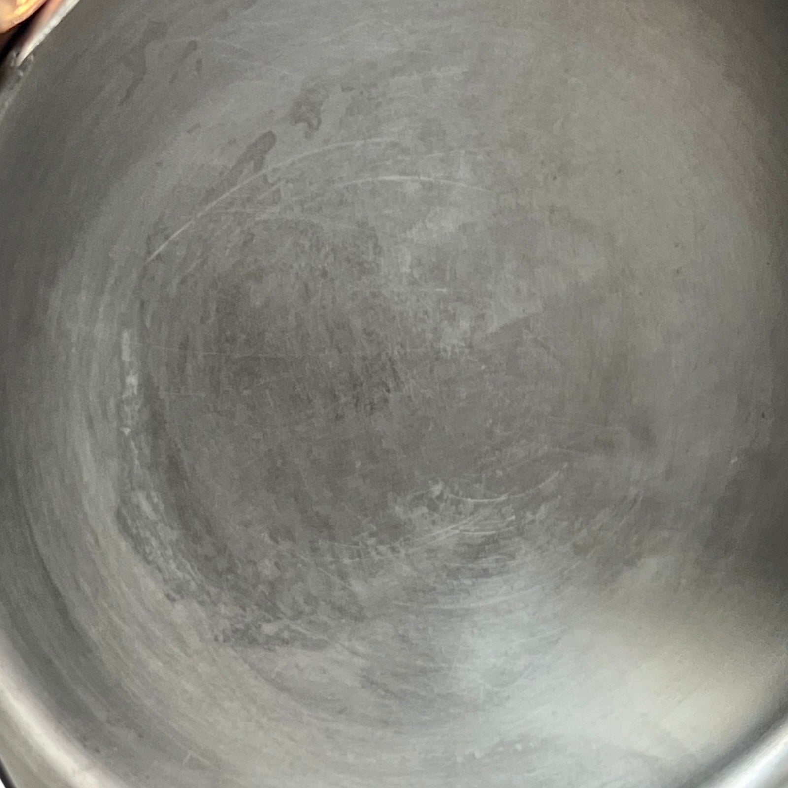 Small copper frying pan with a brass handle and tin lining on a white background