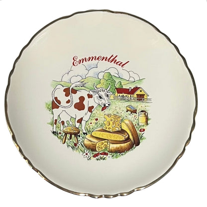 Decorative plate with a cow, cheese, and landscape illustration on a white background