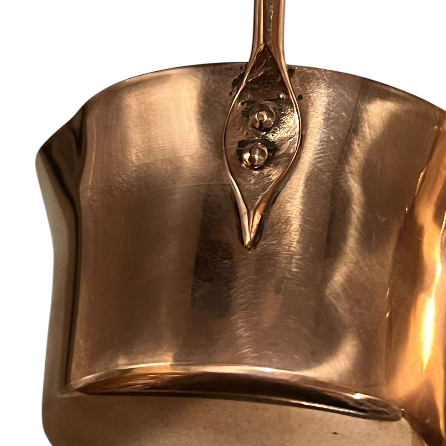 Close up of 3 copper utensils on a copper hanging bar on a white background