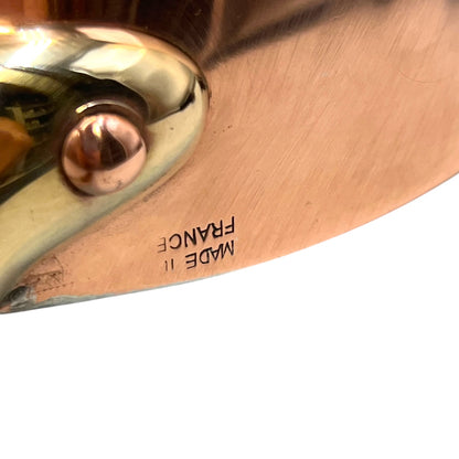Small copper frying pan with a brass handle, Made in France stamp and tin lining on a white background