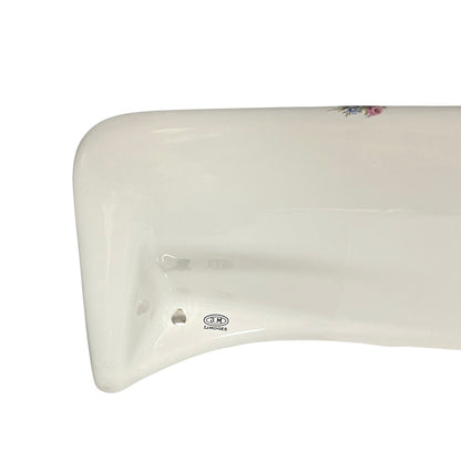 Close-up of a glossy white ceramic shelf corner with a small floral decoration and a visible 'Limoges' brand mark near the bottom.