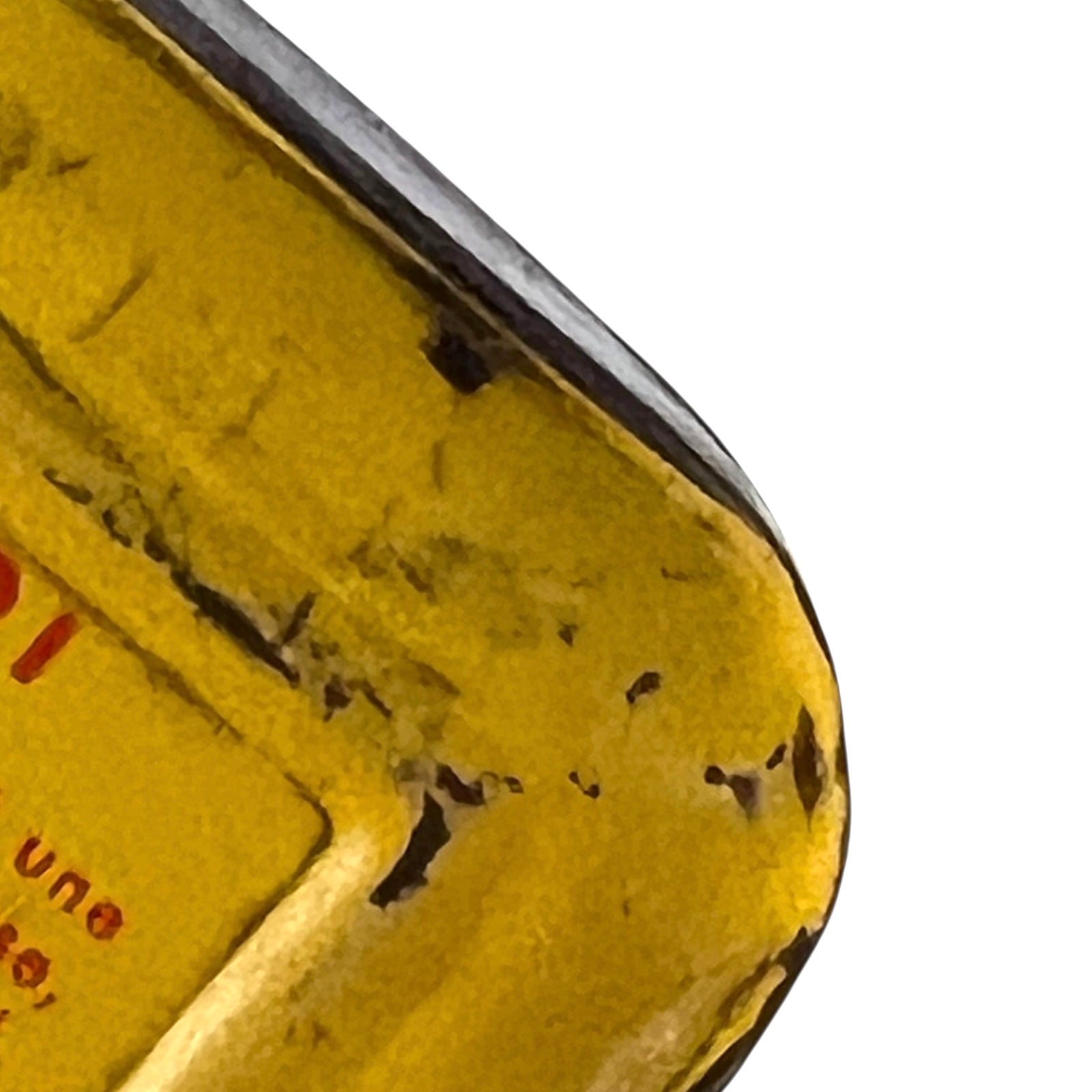 Close-up of a yellow object with text and a metallic edge on a white background