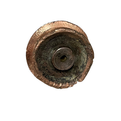 A circular, distressed metal hardware piece with a textured bronze outer rim and a dark, oxidized center, isolated on a white background.