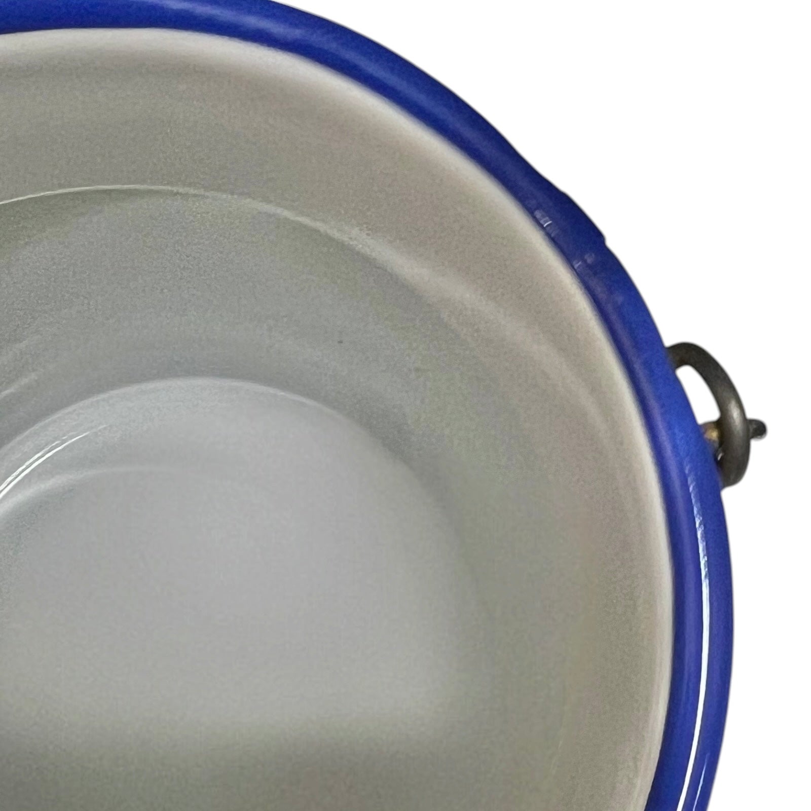 Close-up of the interior of a coffee kettle with a white enamel-like surface and a blue rim, plus a small metal handle visible on the right side.