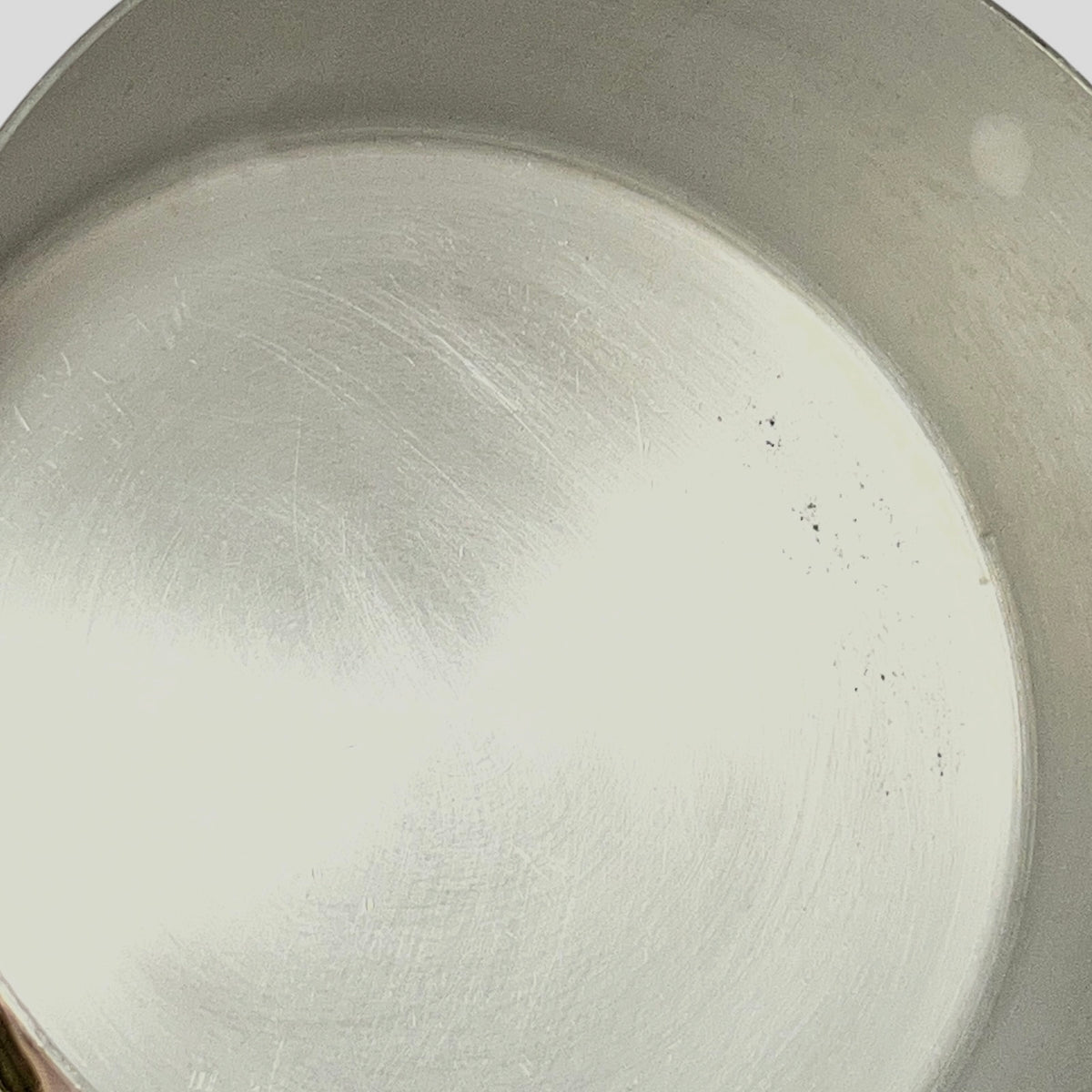 Close-up of the inside of a brushed metal pot or pan showing a scratched aluminium surface.