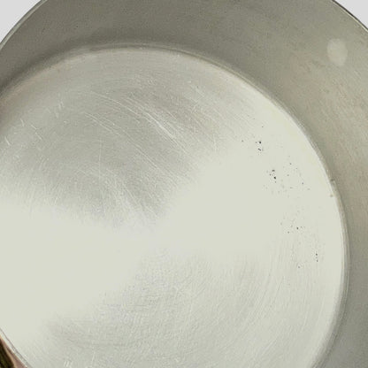 Close-up of the inside of a brushed metal pot or pan showing a scratched aluminium surface.