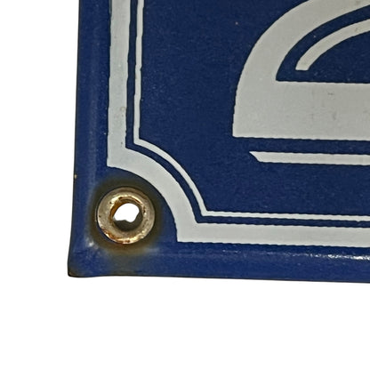 Close-up of the bottom-left corner of a blue metal sign with a white decorative border and a pre-drilled hole for hanging, shown on a white background.