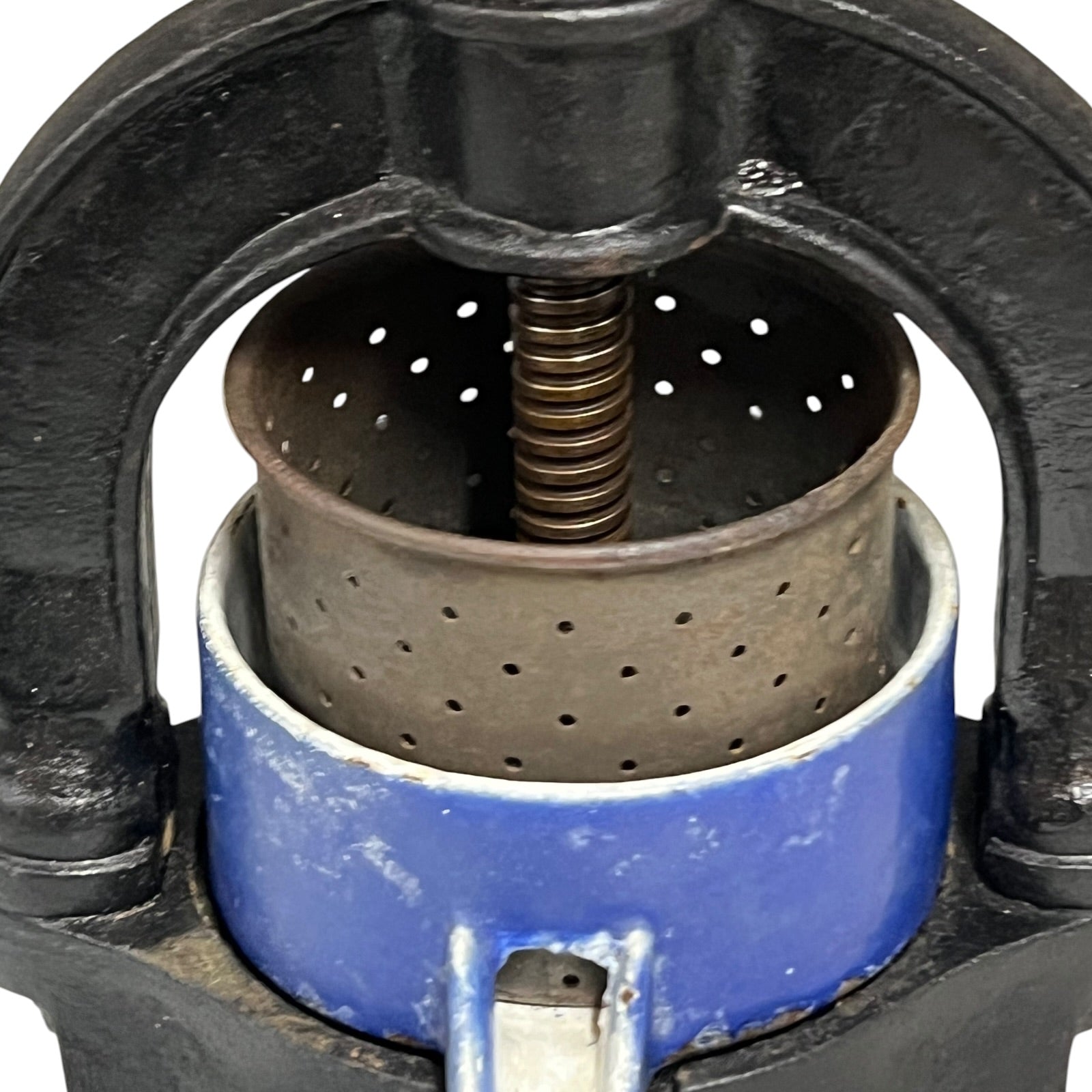 Close-up of a vintage fruit press with a black handle on a white 
