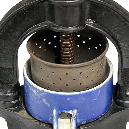 Close-up of a vintage fruit press with a black handle on a white 