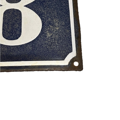 Close up of a blue enamel sign with a white number 18 on a white background 