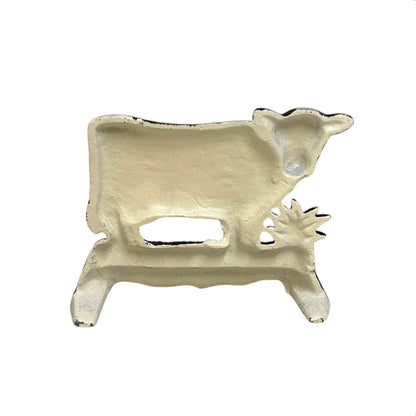 Close up of small cow shaped cast iron doorstop on a white background