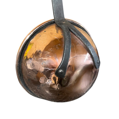 A hammered copper hanging pan with a dark metal loop and bracket, shown against a plain white background.