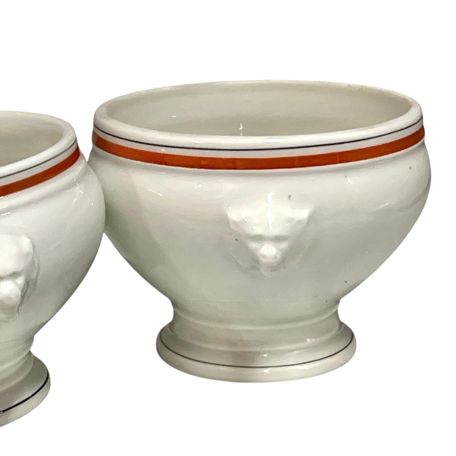 White ceramic footed bowls with lion head handles on a white background