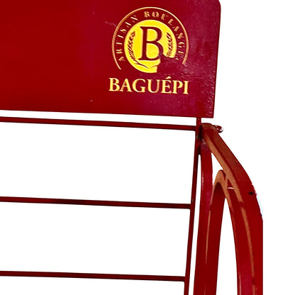 Close-up of a red metal display rack with a yellow circular logo on the back panel, against a white background.