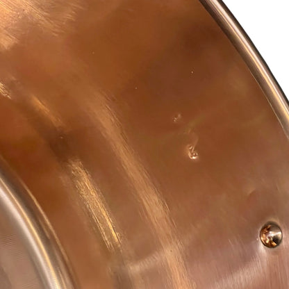 Close up of French copper bowl upcycled into a copper sink with iron handles and a chrome pop up waste on a white background
