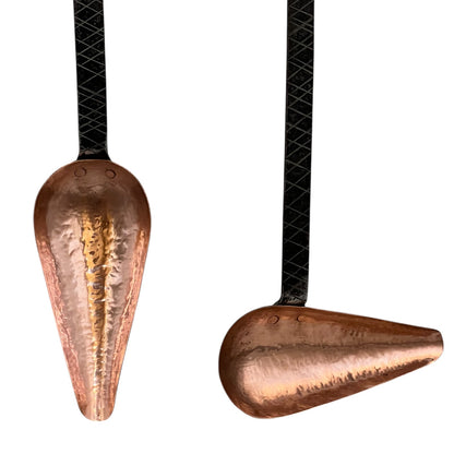 Close up of French copper kitchen utensils with black handles on a white background