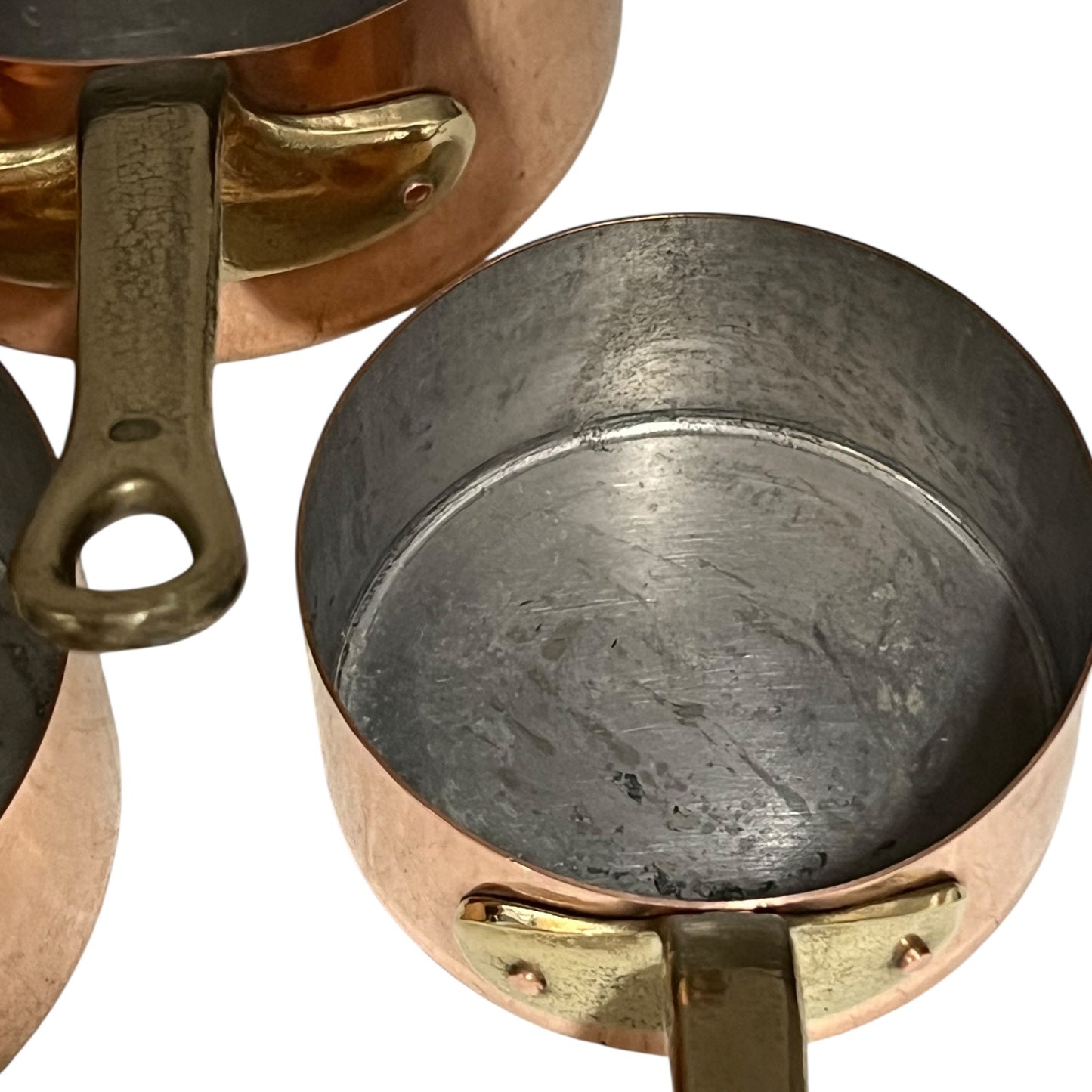 Close-up of a copper pot with a brass handle and tin lining on a white background