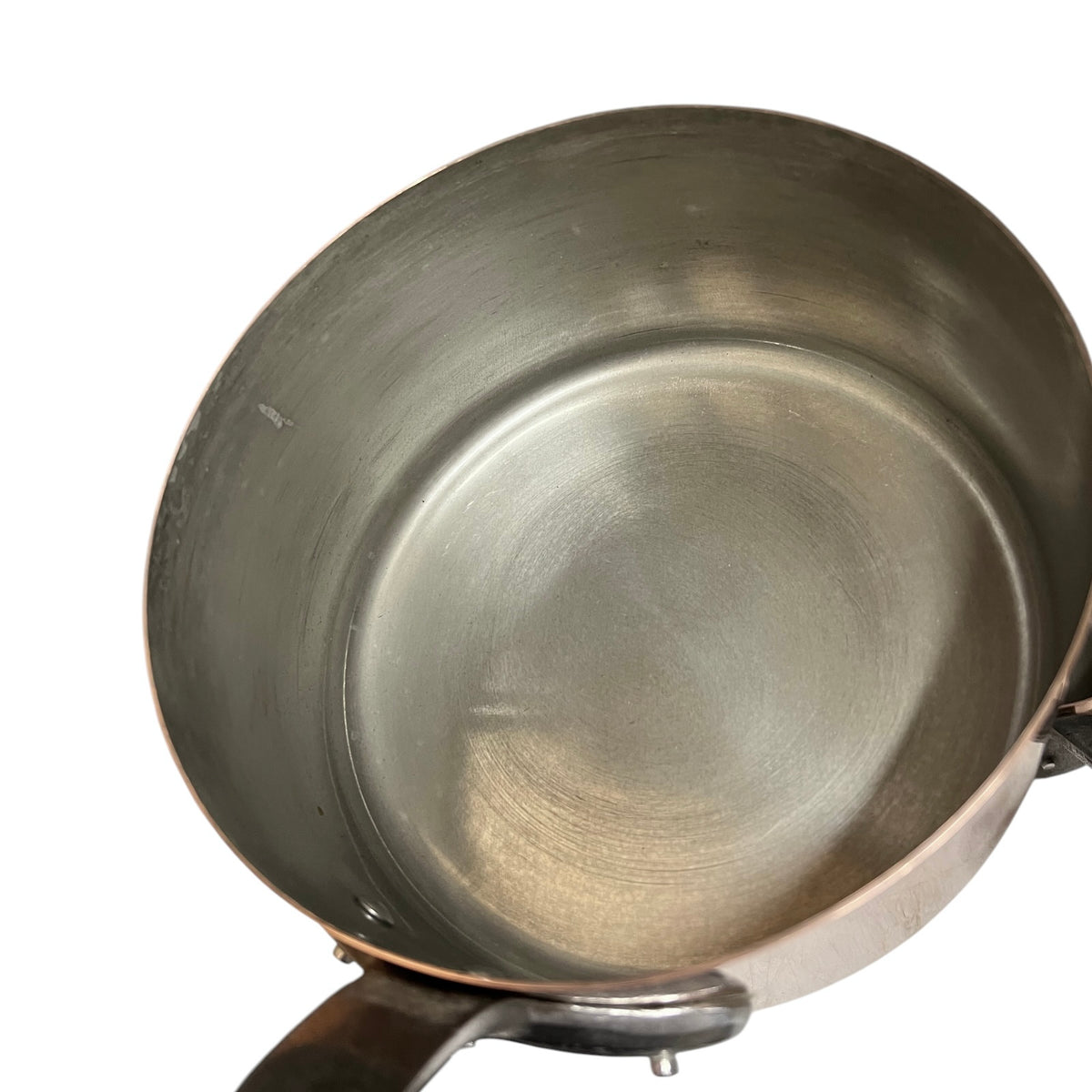A close-up top-down view of a copper tin lined saucepan or pot with a brushed metal interior and a copper-toned exterior rim, shown on a white background.