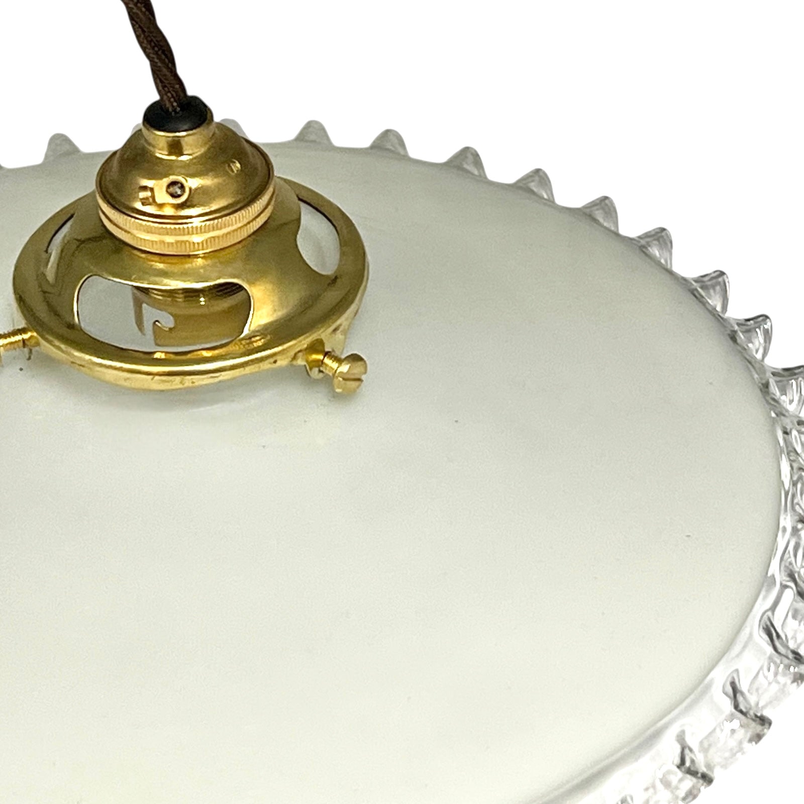 close up of brass ceiling light fixture with white glass shade on a white background