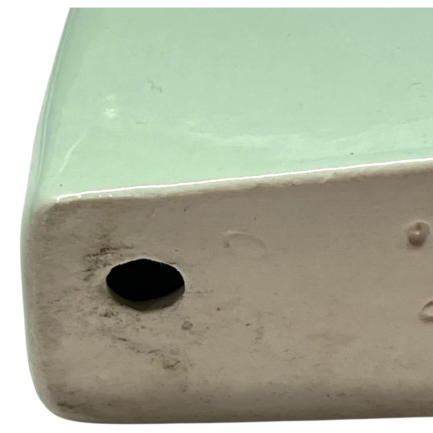back view of pale green ceramic shelf on a white background