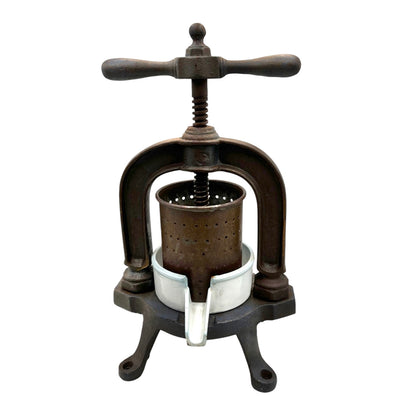 Vintage French cast iron metal fruit press with a white enamel container on a white background