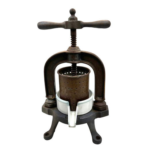 Vintage French cast iron metal fruit press with a white enamel container on a white background
